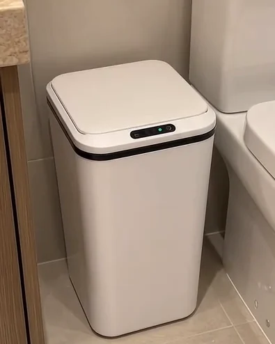 Lixeira branca fechada ao lado do vaso e da bancada