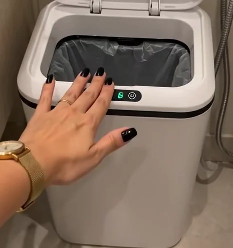 Mão próxima ao sensor, com o aro e a tampa da lixeira à vista